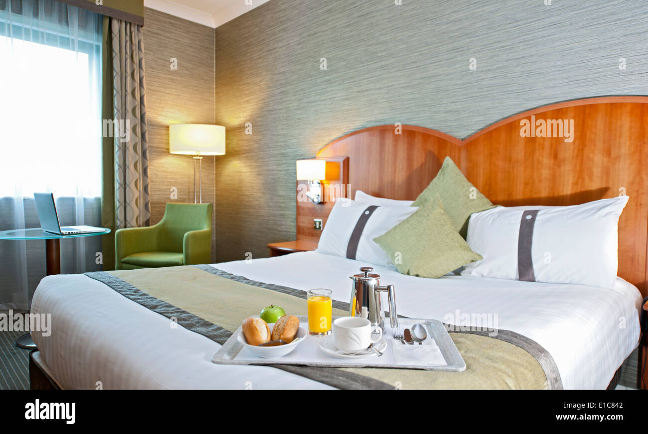 Plateau de petit-déjeuner sur le côté d'un lit dans une chambre d'hôtel Banque D'Images Plateau de petit-déjeuner sur le côté d'un lit dans une chambre d'hôtel Banque D'Images