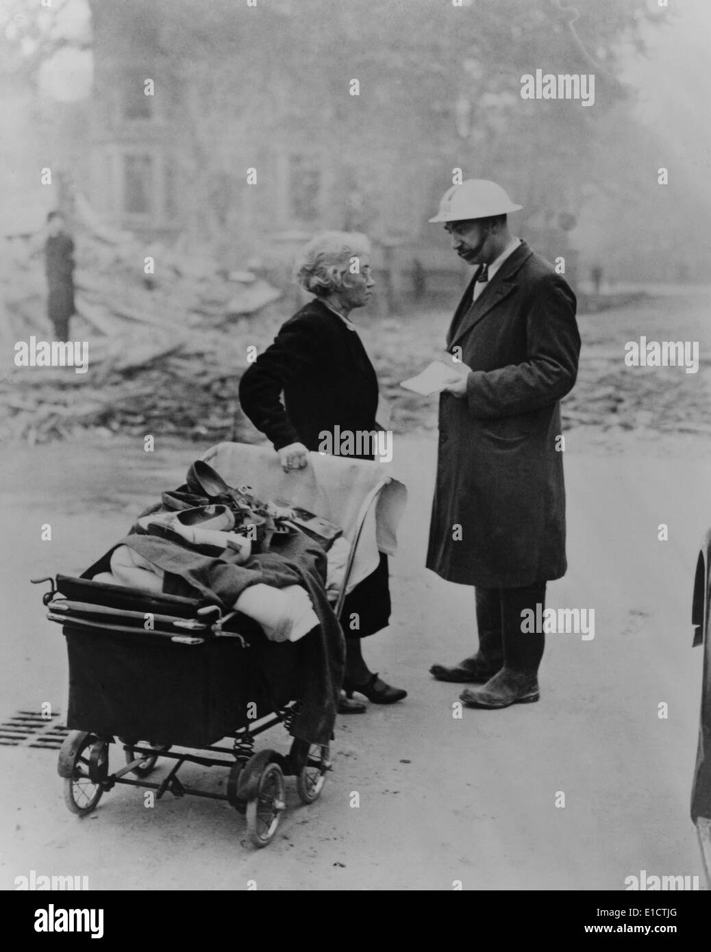 Un Londres bombardé des femmes transportant quelques effets personnels des entretiens avec un travailleur Précautions des raids aériens. Au cours de la bataille de 1940 Banque D'Images