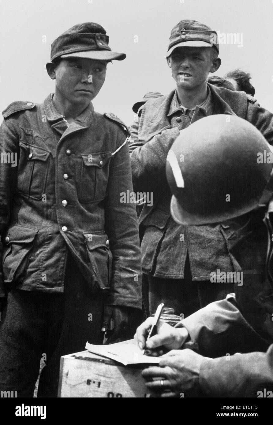 De jeunes japonais, vêtu d'un uniforme nazi, était parmi les prisonniers allemands capturés sur les plages de France. Le capitaine de l'armée américaine est Banque D'Images