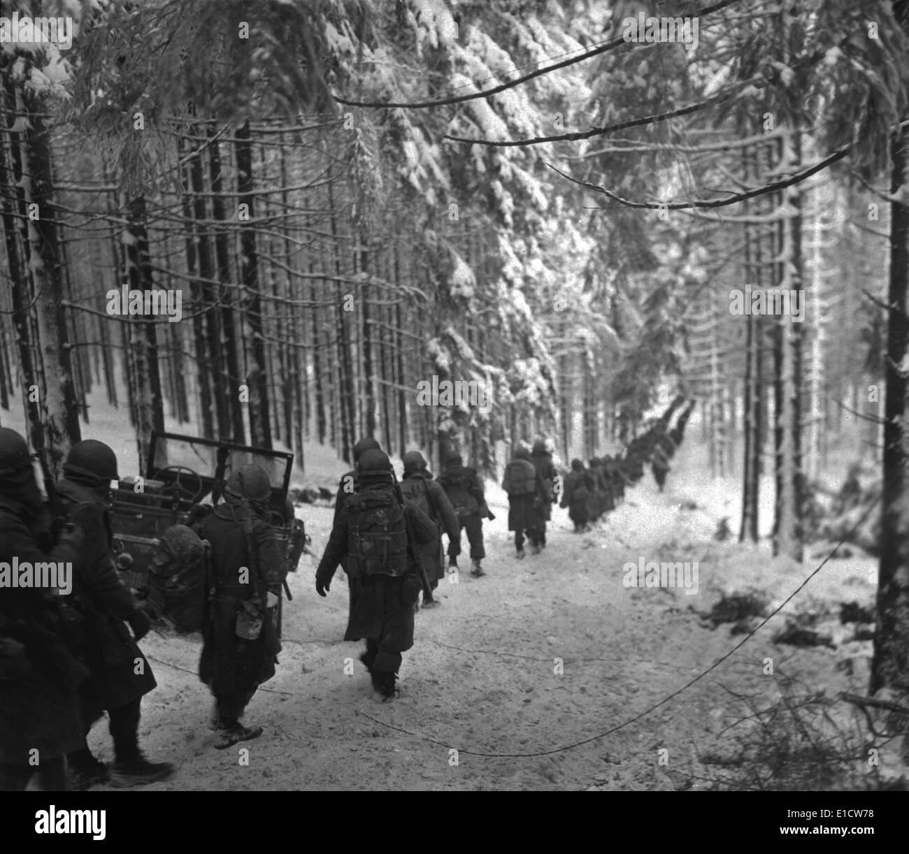 Des soldats américains mars le long de la route couverte de neige dans la Bataille des Ardennes. Ils avançaient pour bloquer l'armée allemande en retraite Banque D'Images