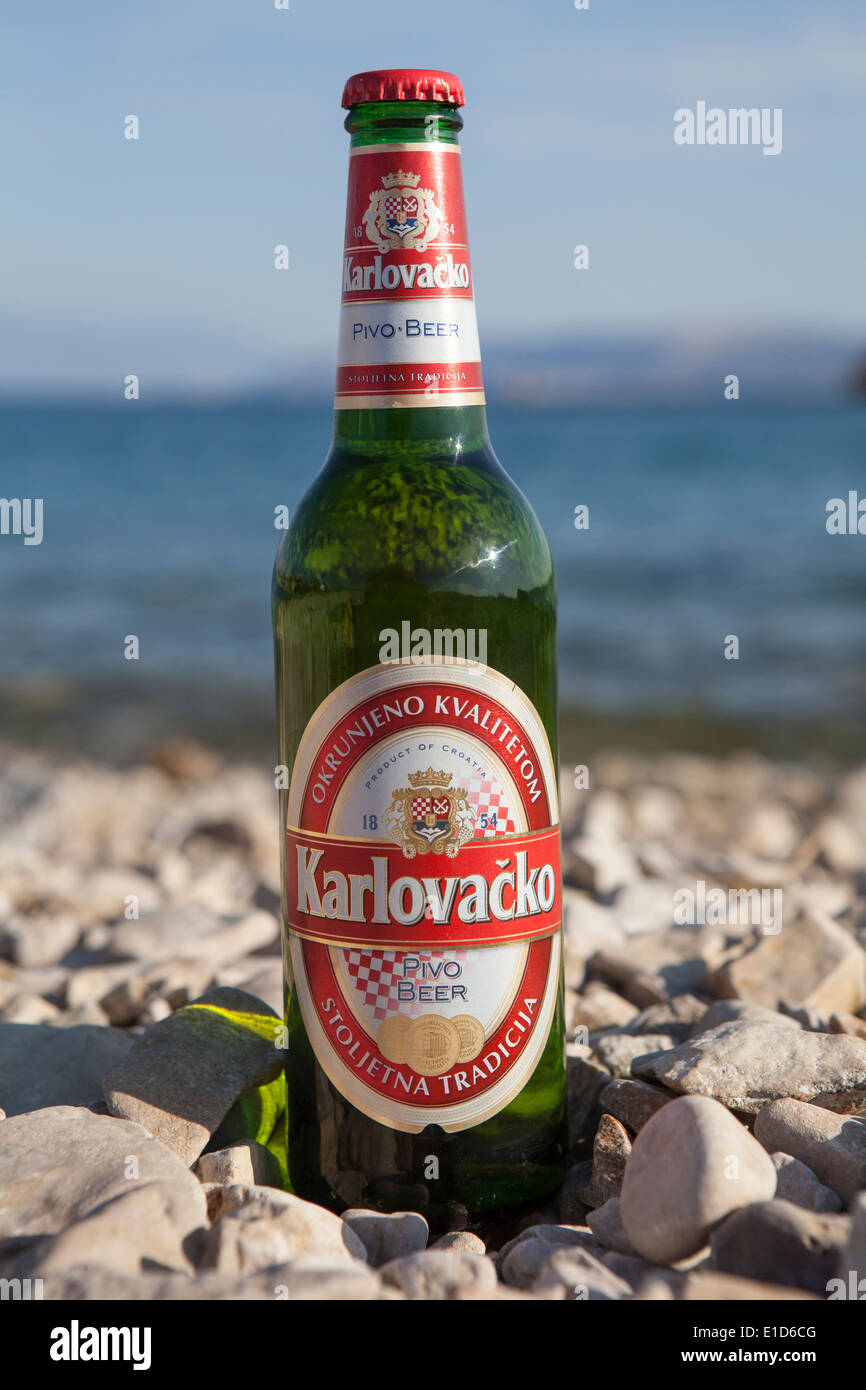 Bouteille de bière croate Karlovacko, populaire, sur une plage de galets. Banque D'Images