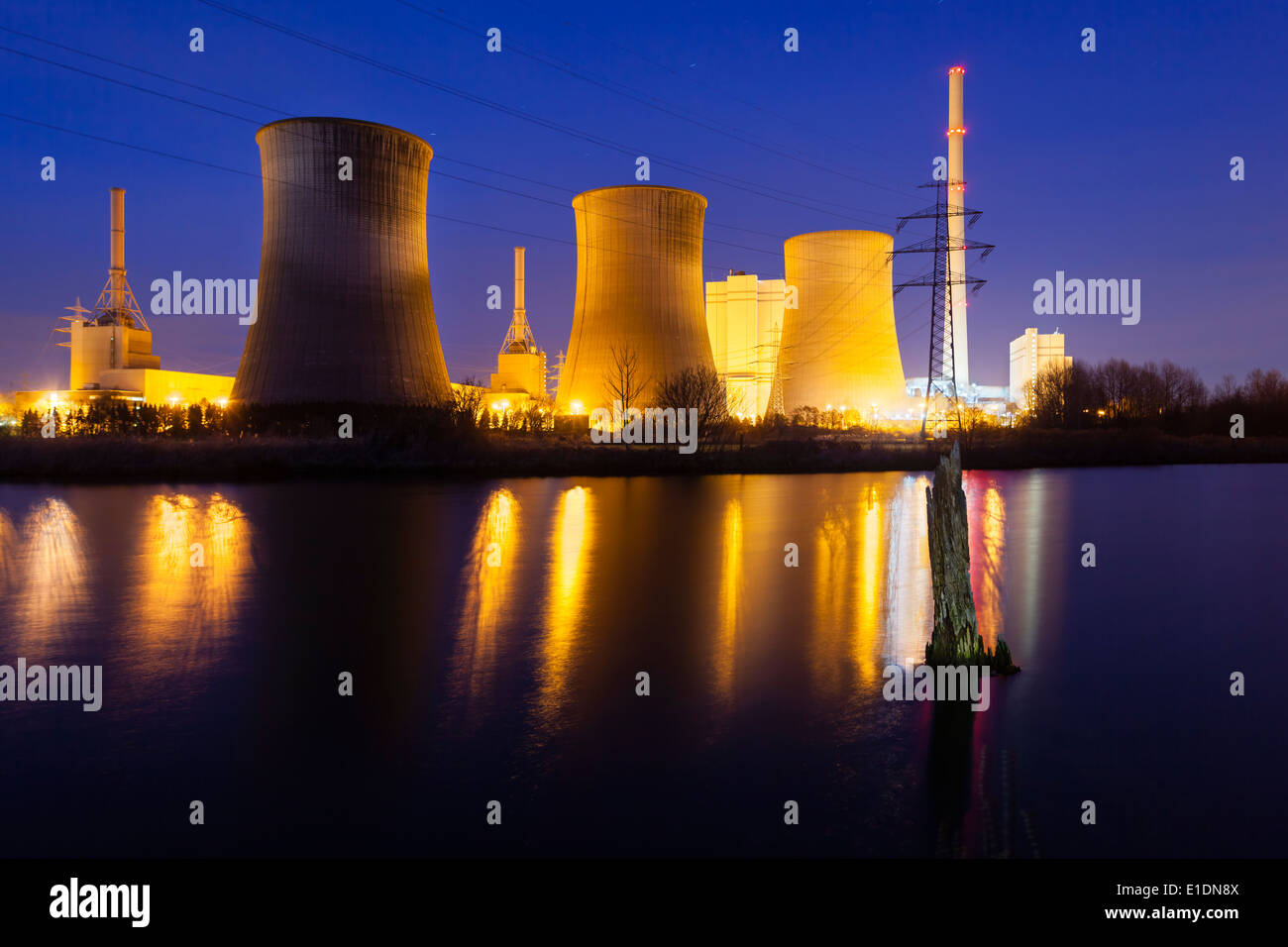 Une centrale électrique au charbon dans la rivière paysage avec des arbres morts dans la nuit Banque D'Images