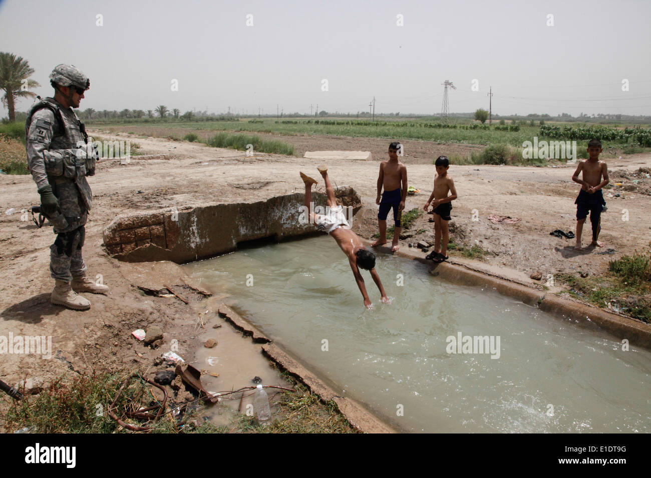 Le capitaine de l'armée américaine Andrew Lewis regarde les garçons irakiens jouer dans un canal dans le mollah Fayyed, l'Iraq, le 6 juin 2010. Lewis, qui est command Banque D'Images