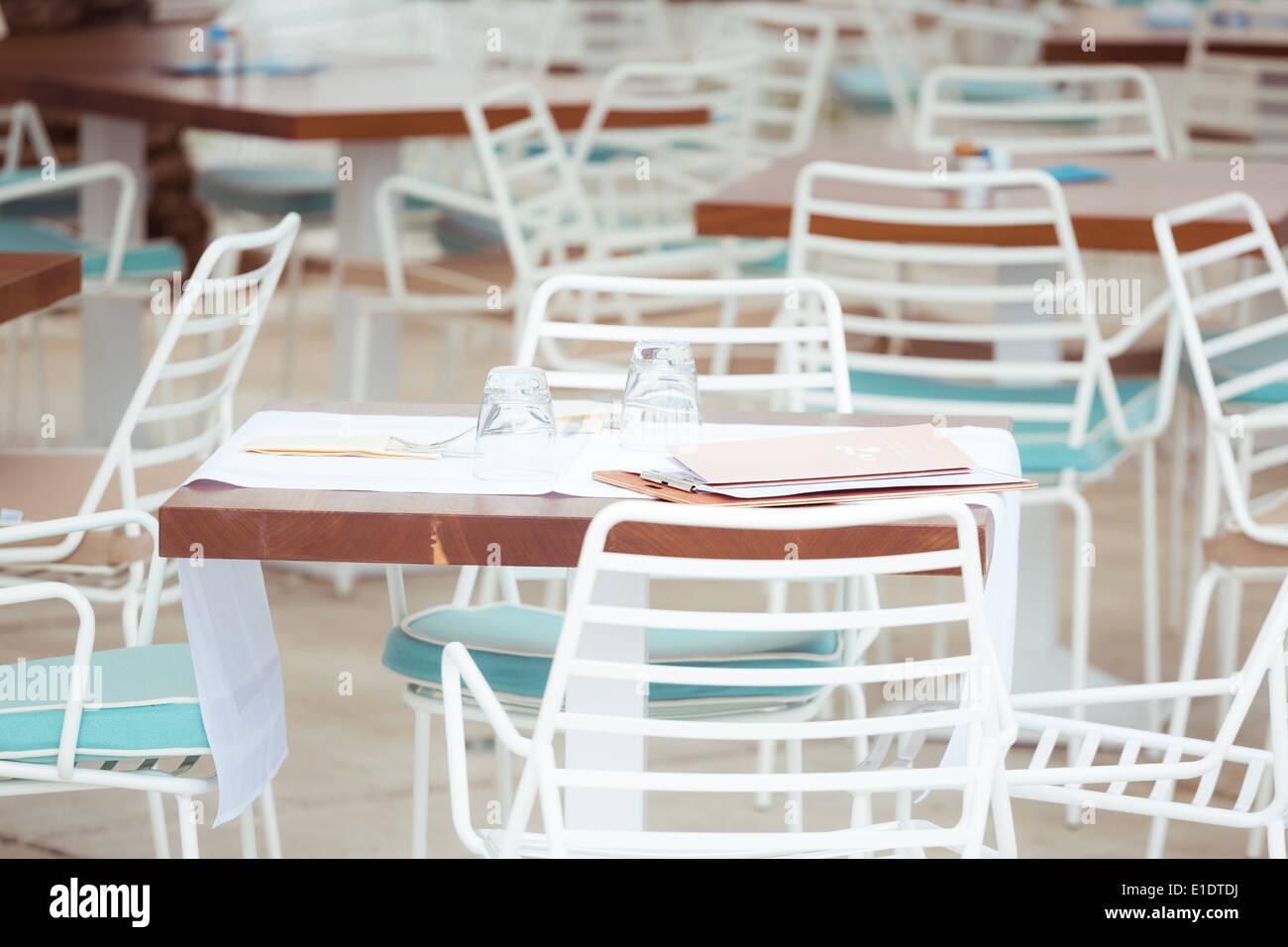 Tables en bois et chaises encadrées blanc organisé dans un café à Split en Croatie. Un menu et des verres sont sur la table Banque D'Images