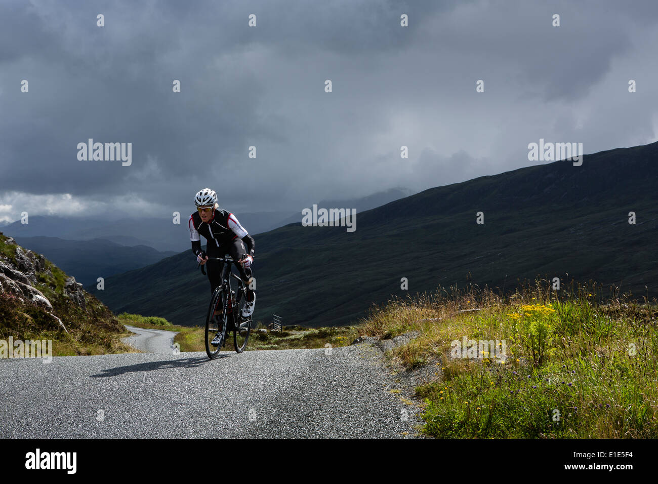 Cresting cycliste une colline sur l'île de Skye avec en arrière-plan un ciel orageux Banque D'Images