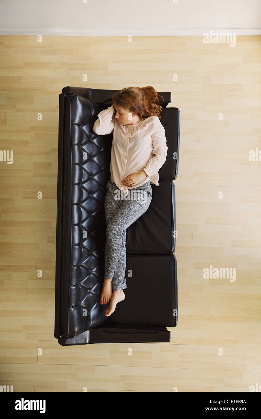Top View of young woman lying on a couch de prendre une sieste. Les femmes de race blanche de dormir sur un canapé à son appartement. Banque D'Images
