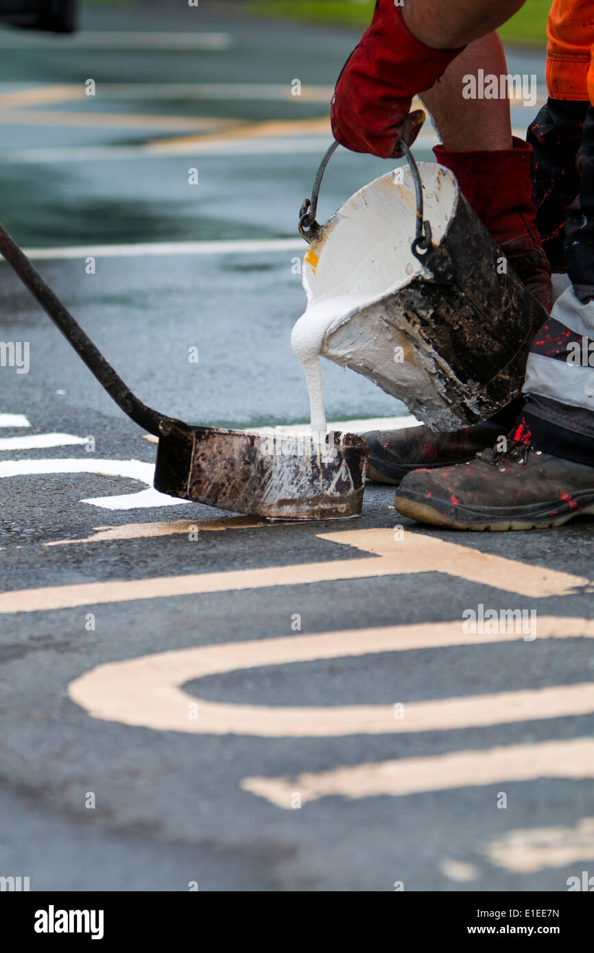 Les travailleurs utilisent une base de plastique chaud bouillant pour marquer une route. Banque D'Images