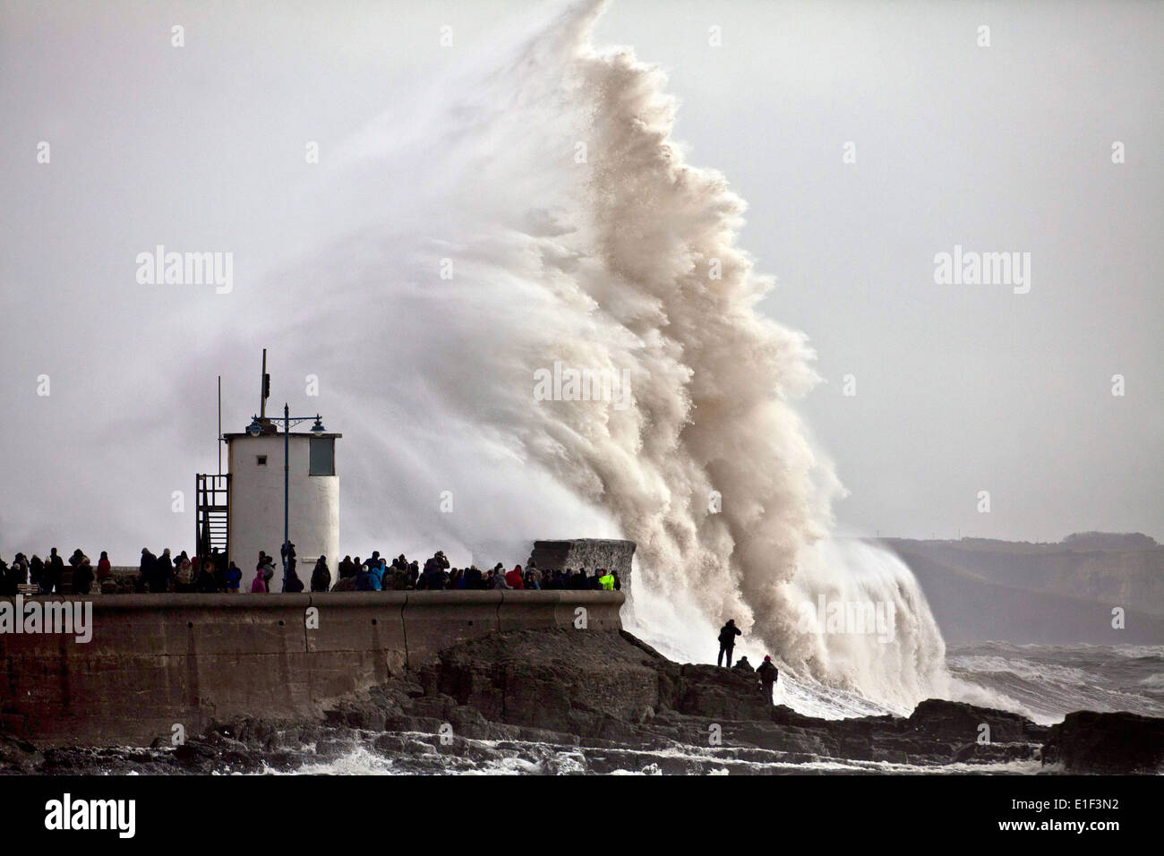 Des dizaines de personnes pack la digue à Porthcawl en Galles du Sud pour regarder les énormes vagues qui le phare Banque D'Images