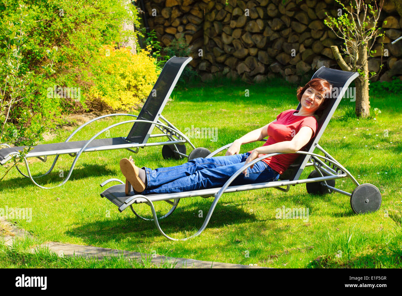 Vous pourrez vous détendre. Mature Woman resting on the black chaise longue dans le jardin. Printemps ou l'été. Piscine en plein air. Banque D'Images