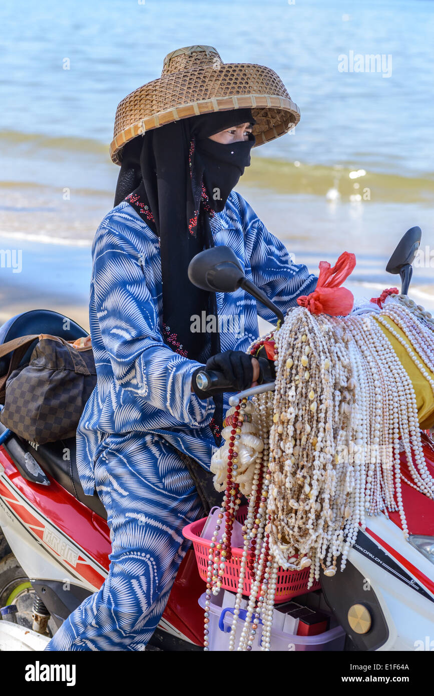 Un musulman hawker est à vendre des babioles sur une moto sur la plage. Banque D'Images