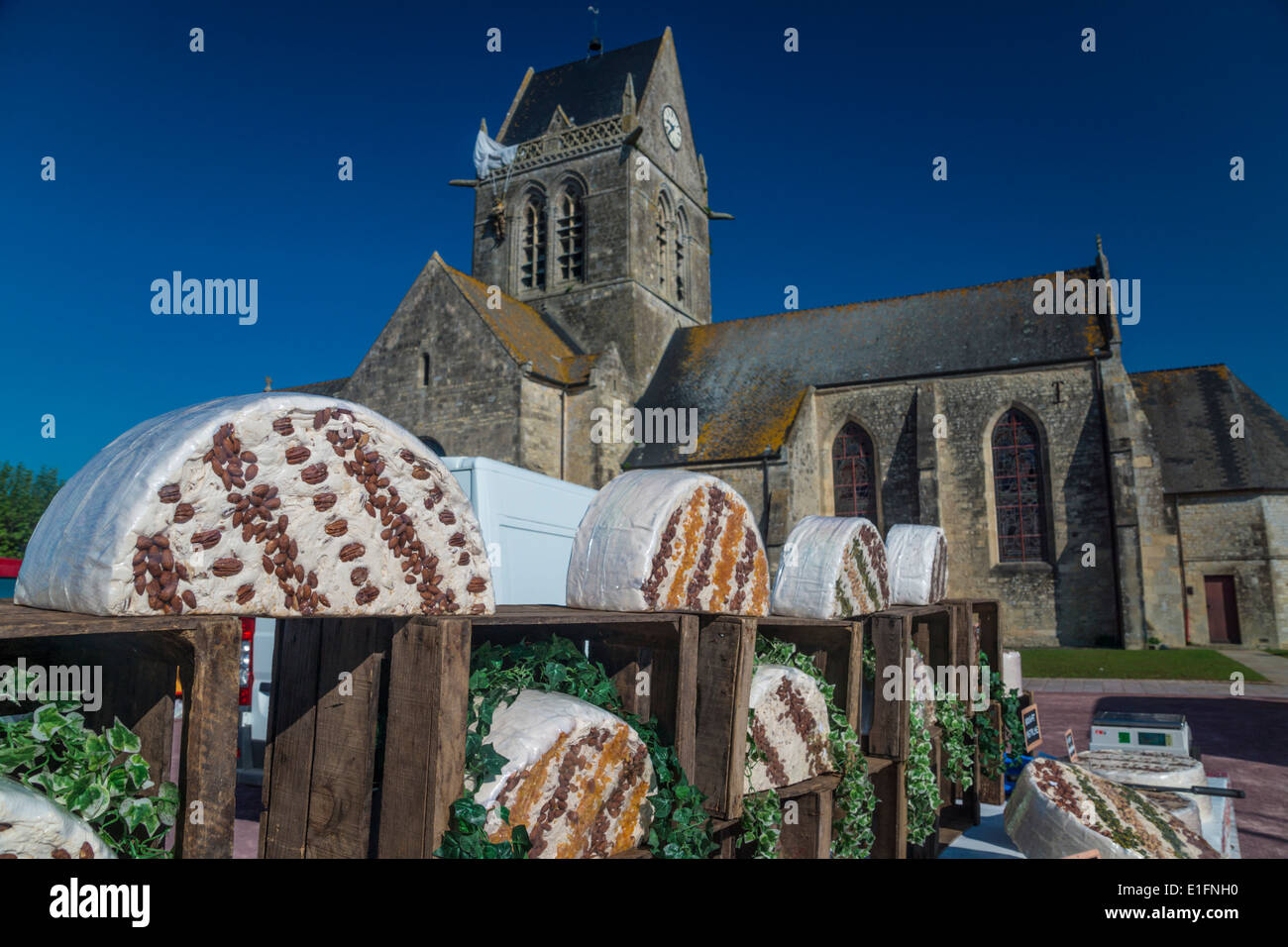 Jour de marché à l'Hôpital Sainte-Anne. Mere-Eglise, Normandie. Rouleaux de nougat en face de l'église .Efigy de parachutiste suspendu au clocher. Banque D'Images