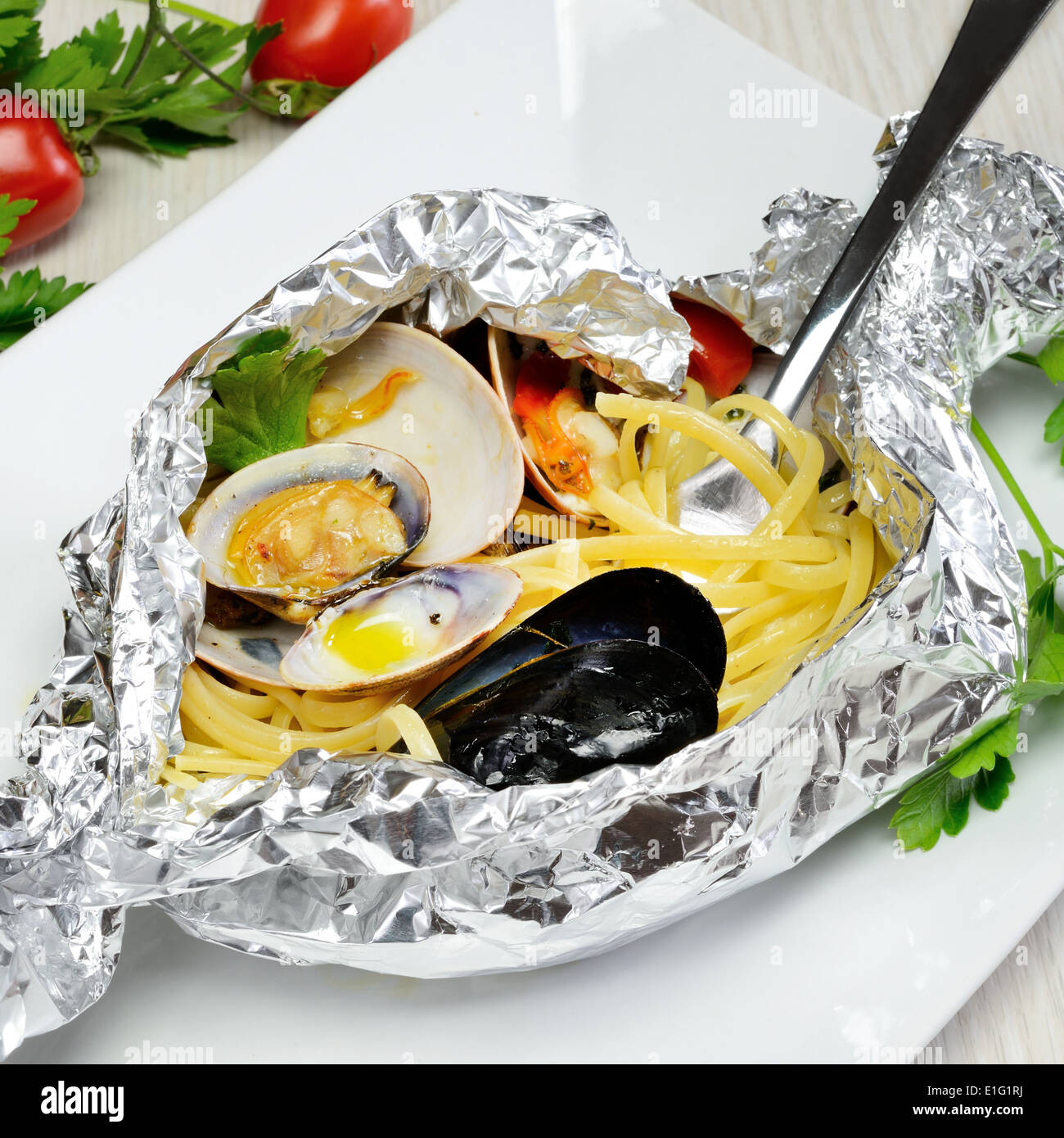 Cuisine traditionnelle italienne composée de pâtes et de fruits de mer spaghetti fasolari,palourdes et moules, cuites au four dans de l'aluminium Banque D'Images