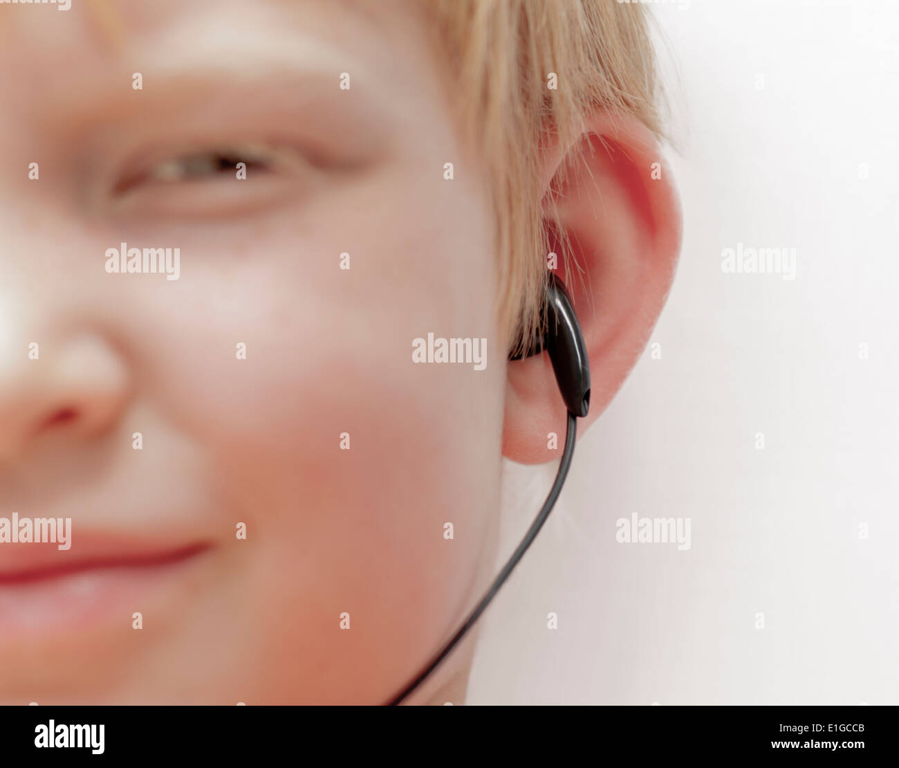Portrait d'un garçon de 7 ans à l'écoute de son lecteur MP3-Player en utilisant les écouteurs intra auriculaires. Banque D'Images