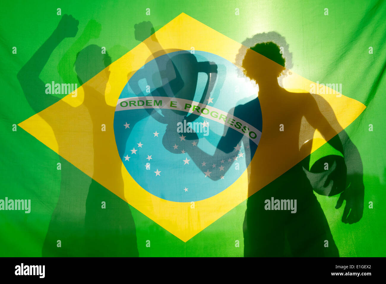Silhouettes d'ombre de joueurs de football célèbre holding trophy et gagnant contre football drapeau brésilien en plein soleil Banque D'Images