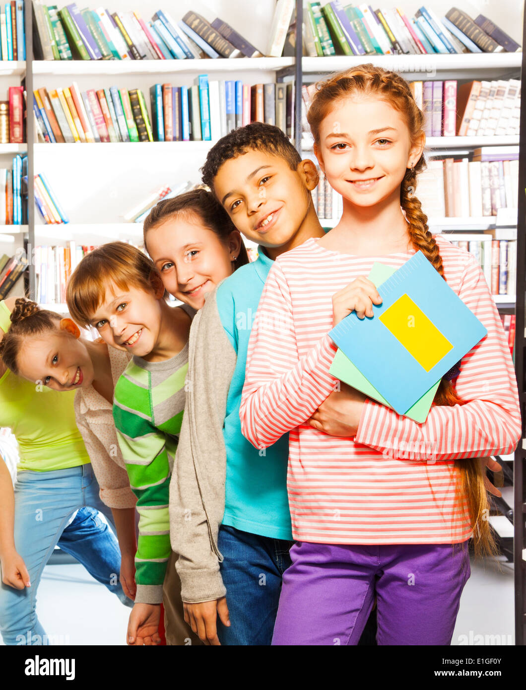 Happy kids comité permanent dans la rangée à l'intérieur bibliothèque Banque D'Images