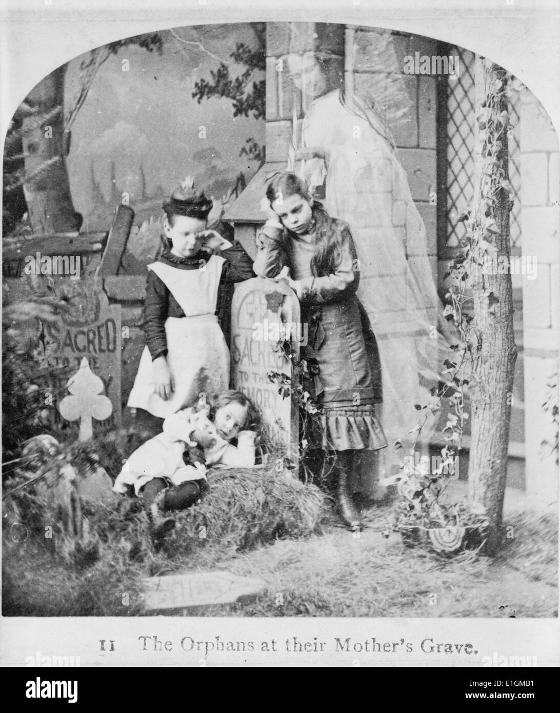 Impression photographique de trois orphelins et le fantôme de leur mère à sa tombe. Datée 1889 Banque D'Images