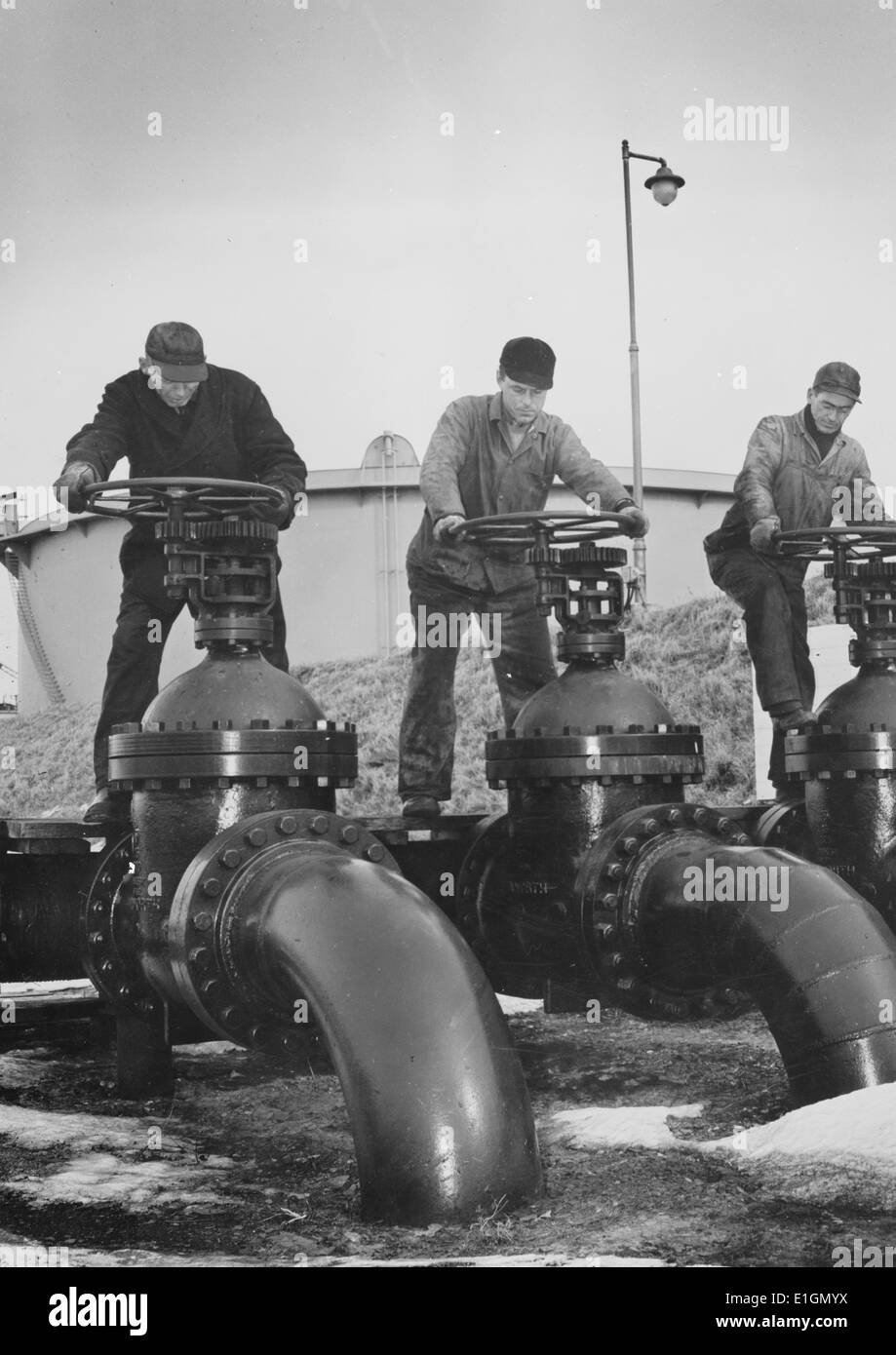 Photo d'hommes au niveau des roues de grandes vannes régulent le flux d'huile dans des pétroliers à un port de la côte atlantique des États-Unis. Datée 1944 Banque D'Images