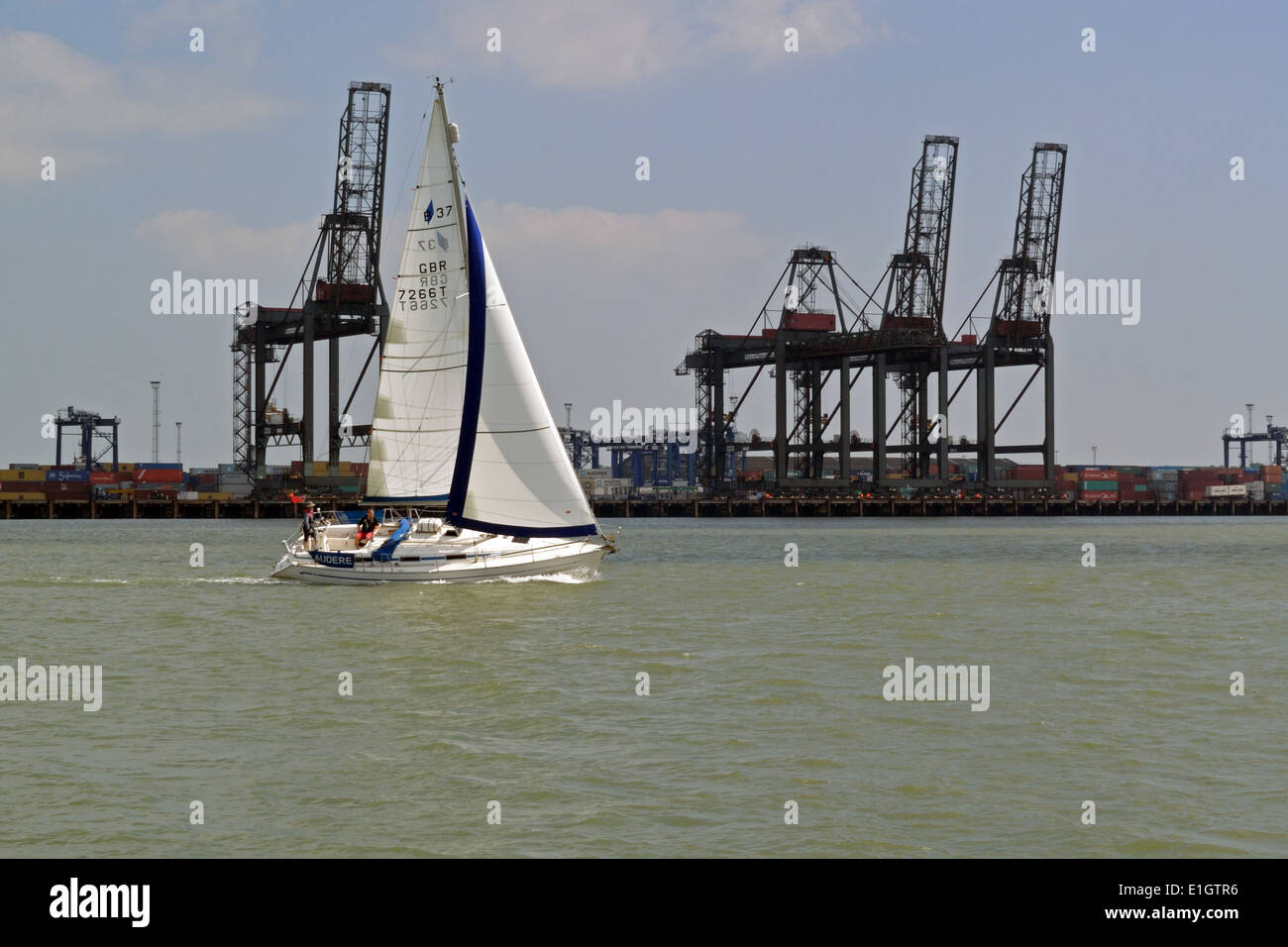 Bateau à voile voyager passé à Felixstowe grues docks, Suffolk, UK Banque D'Images