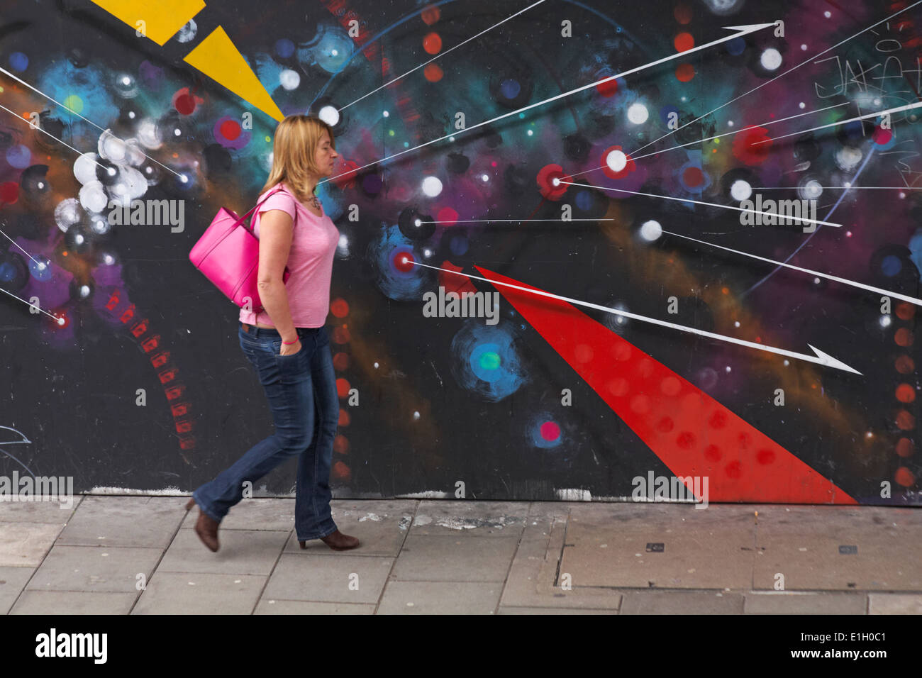 Femme marche passé graffiti street art à Bristol Banque D'Images