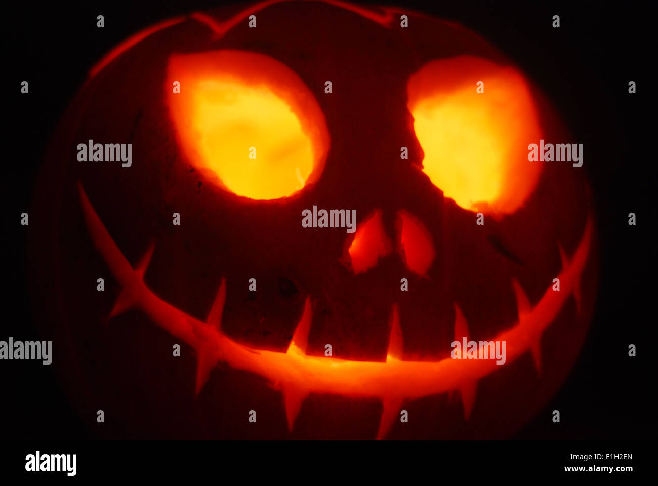 Une citrouille d'Halloween sculptée à la face effrayante illuminée de l'intérieur un arrière-plan noir Banque D'Images