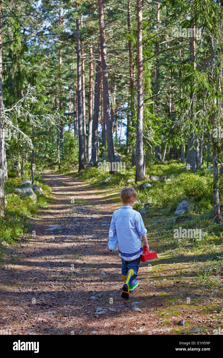 Jeune garçon se promener le long chemin forestier Banque D'Images