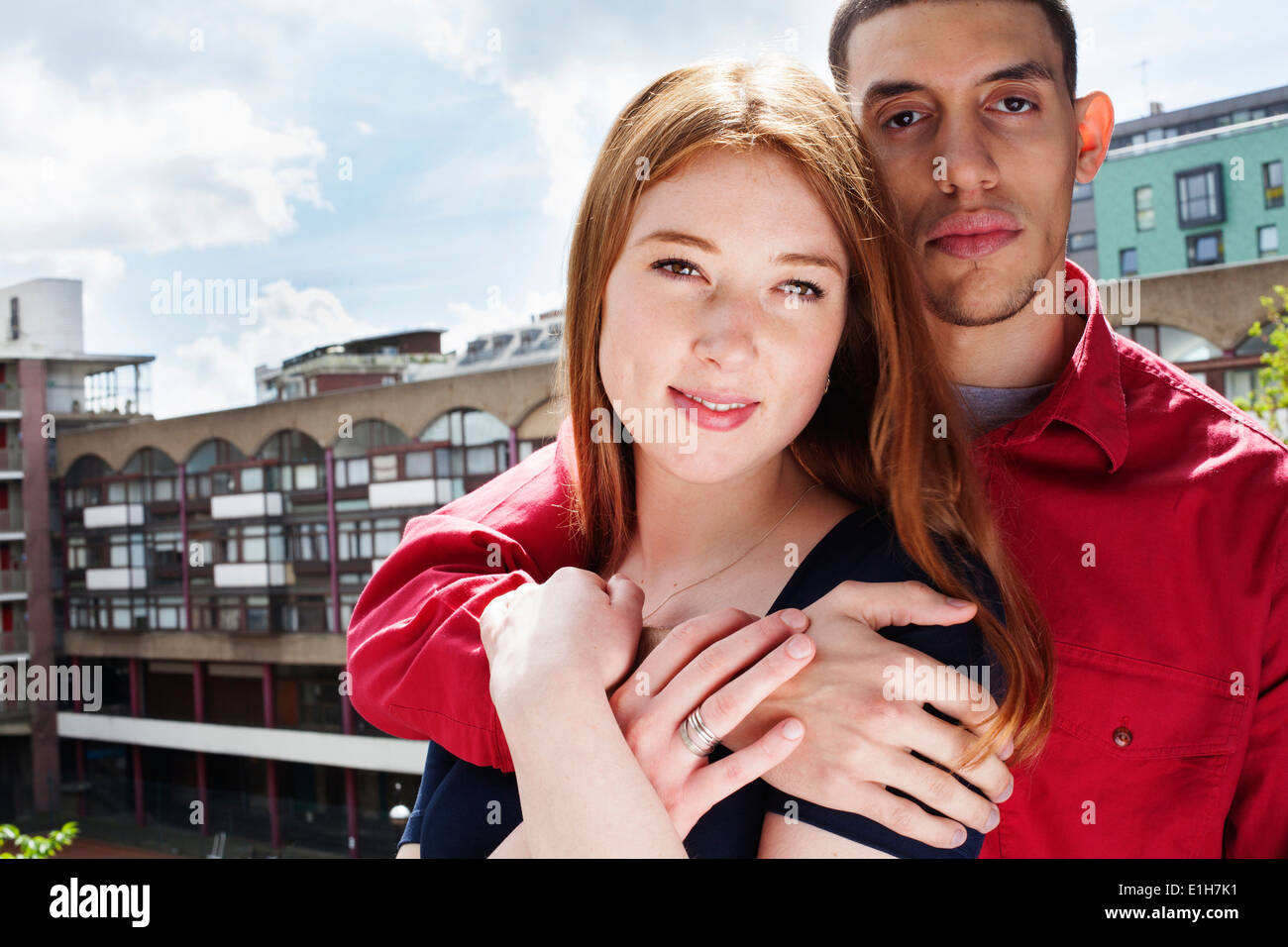 Jeune couple debout sur balcon avec bras autour de Banque D'Images