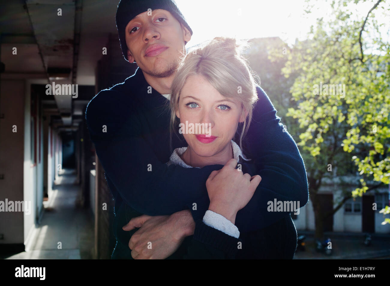 Jeune couple avec bras autour, debout dans le bloc d'appartements, London, UK Banque D'Images