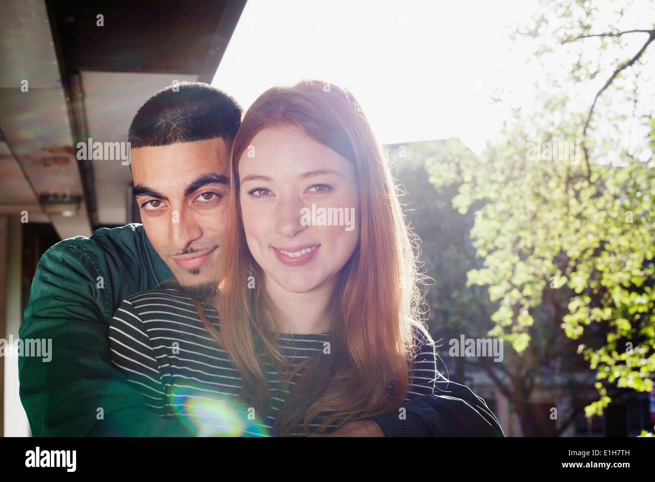 Jeune couple avec bras autour, debout dans le bloc d'appartements, London, UK Banque D'Images