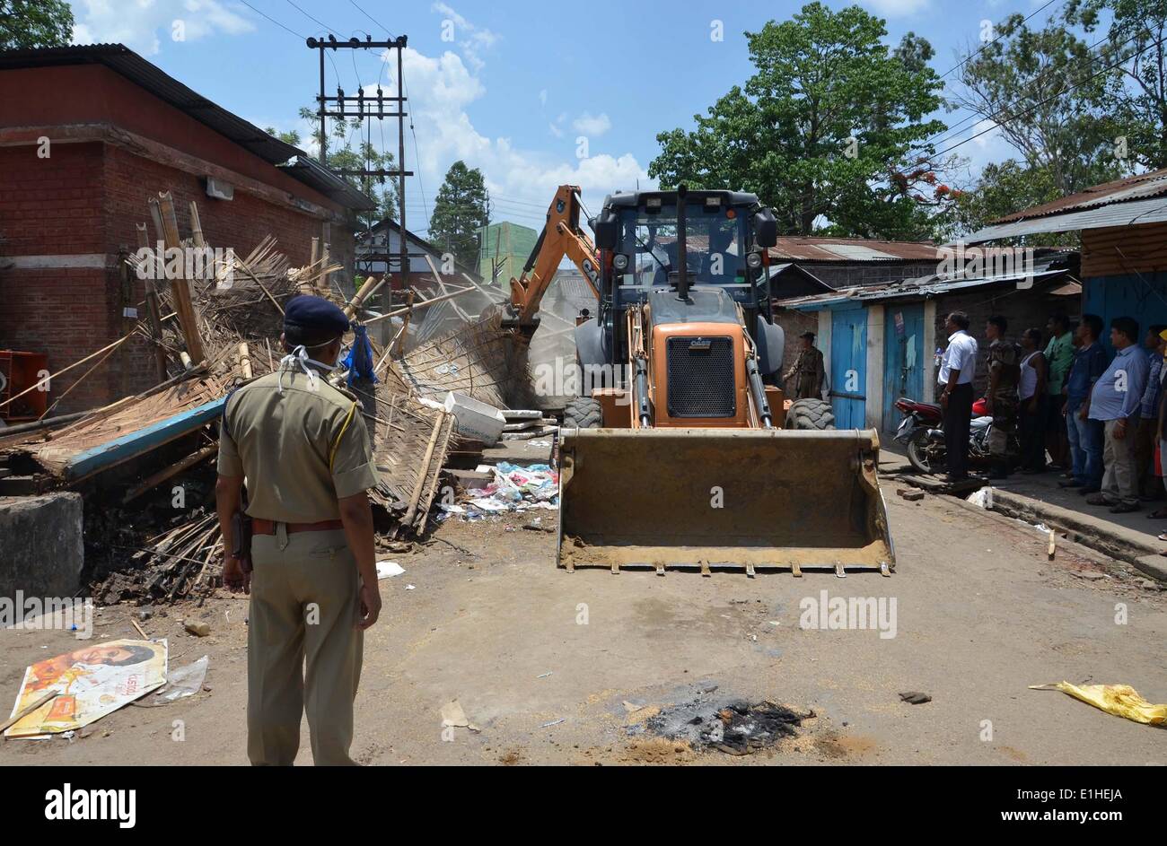 Le Nagaland, l'état indien du Nagaland. 4 juin, 2014. Le personnel de sécurité et les spectateurs regardent un bulldozer démolit une construction illégales au cours d'un entraînement d'expulsion menées conjointement par l'Autorité des chemins de fer indiens et Nagaland entrepreneur ferroviaire Union européenne le long de la gare de Jodhpur, au nord est de l'état indien du Nagaland, le 4 juin 2014. © Caisii Mao/Xinhua/Alamy Live News Banque D'Images