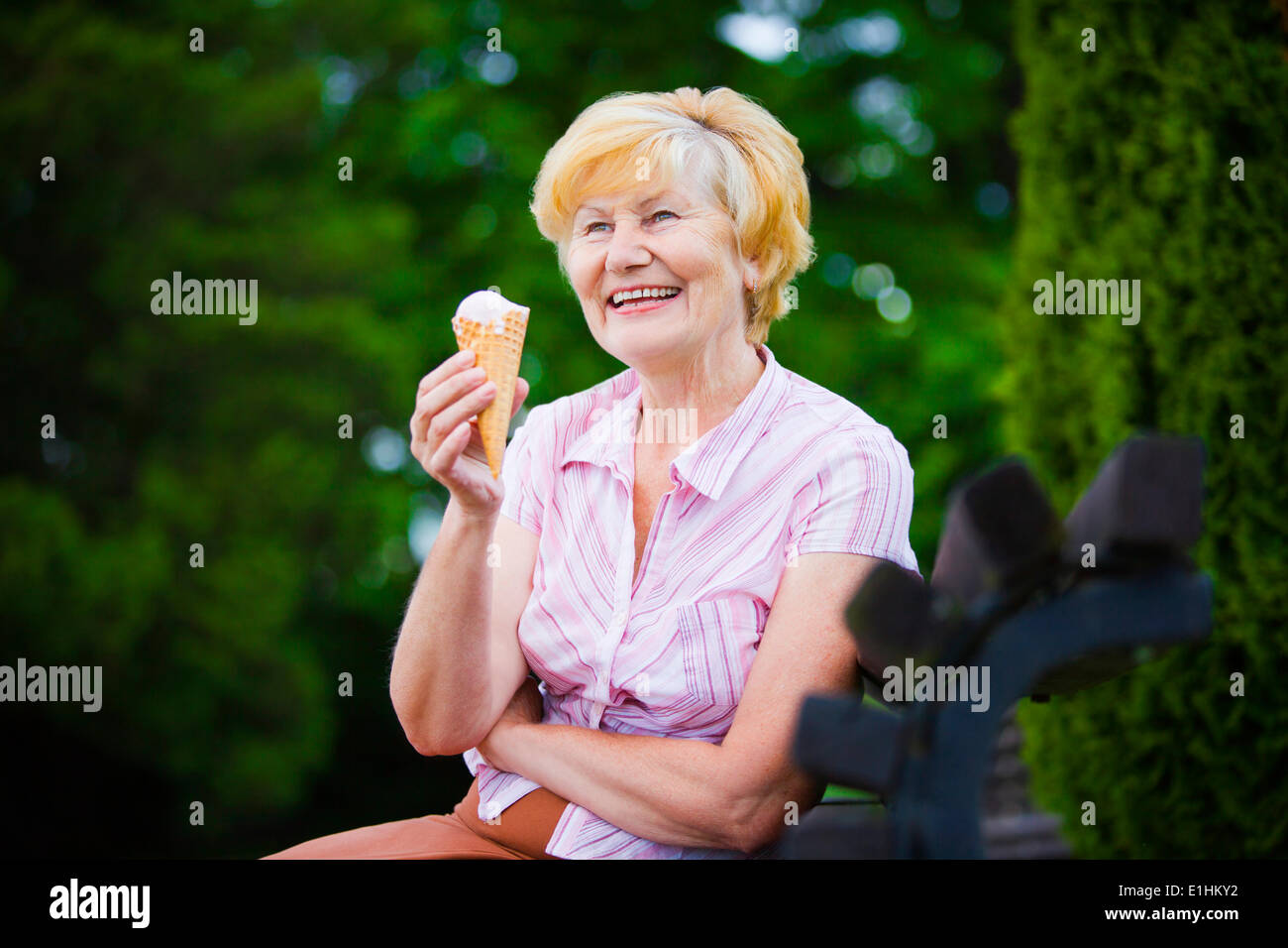 Femme Gray-Haired Crème glacée avec détente sur un banc dans le parc Banque D'Images