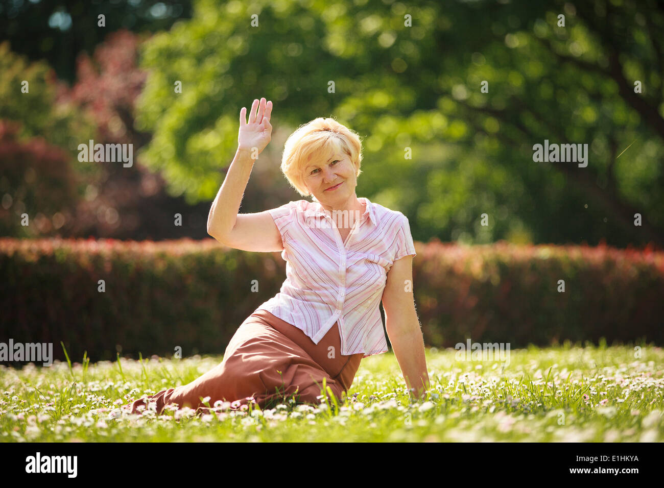 L'échéance. Cheveux Blancs européens Woman sitting on Grass et d'avoir du plaisir Banque D'Images