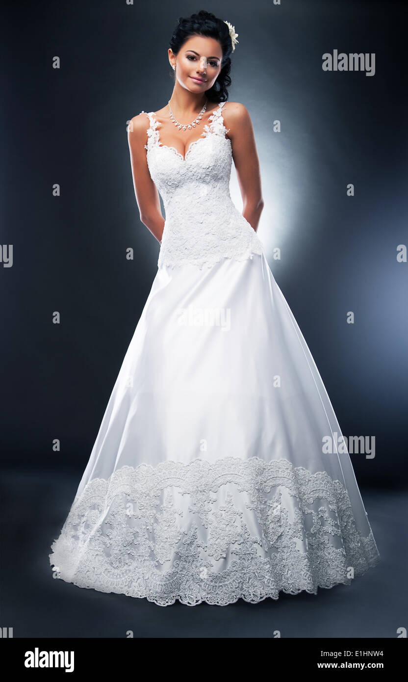 Attractive brunette model en robe de mariée blanche avec une fleur dans la tête posant en studio Banque D'Images