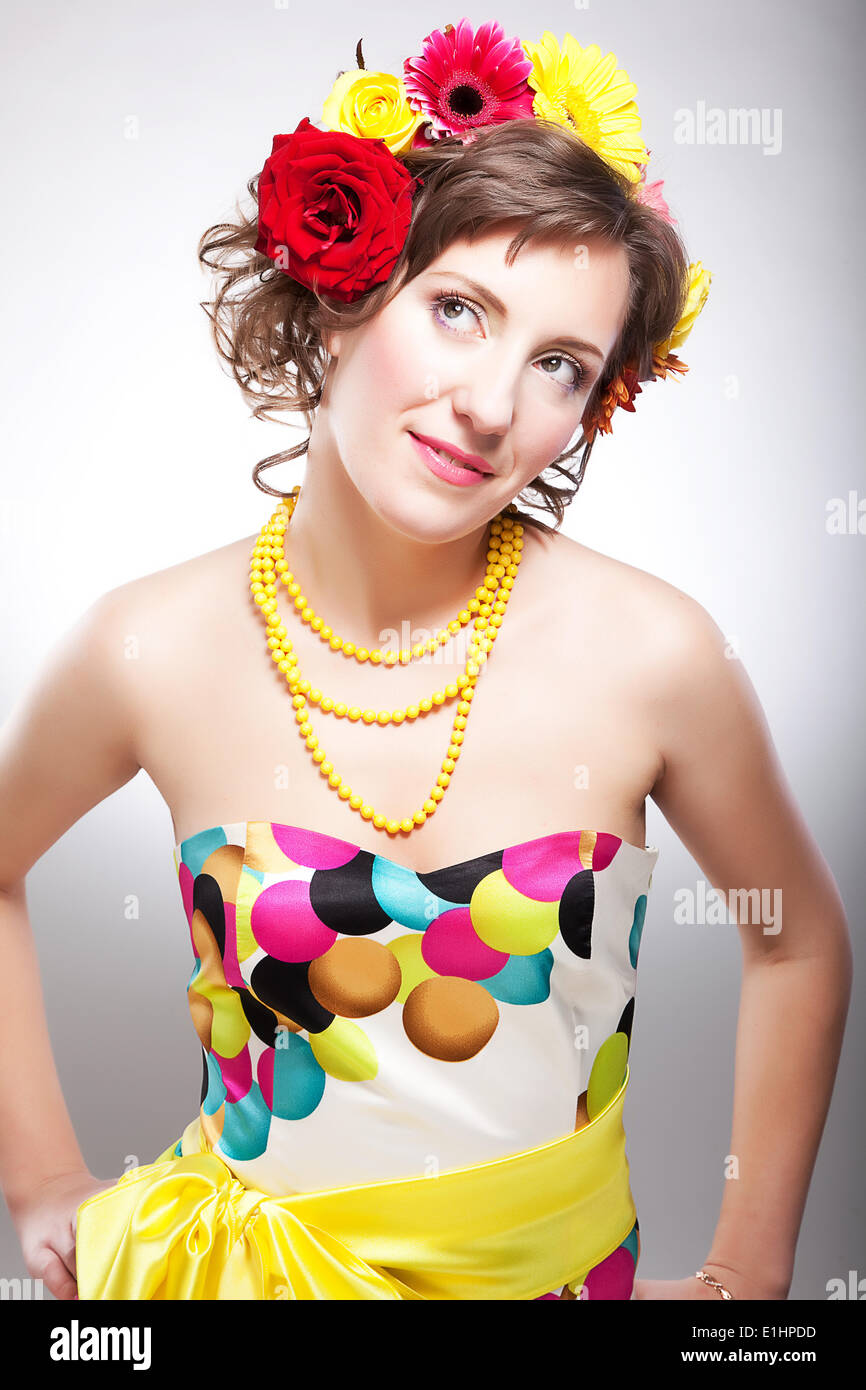 Belle jeune femme en robe multicolore lumineux posant avec fleurs - série de photos Banque D'Images