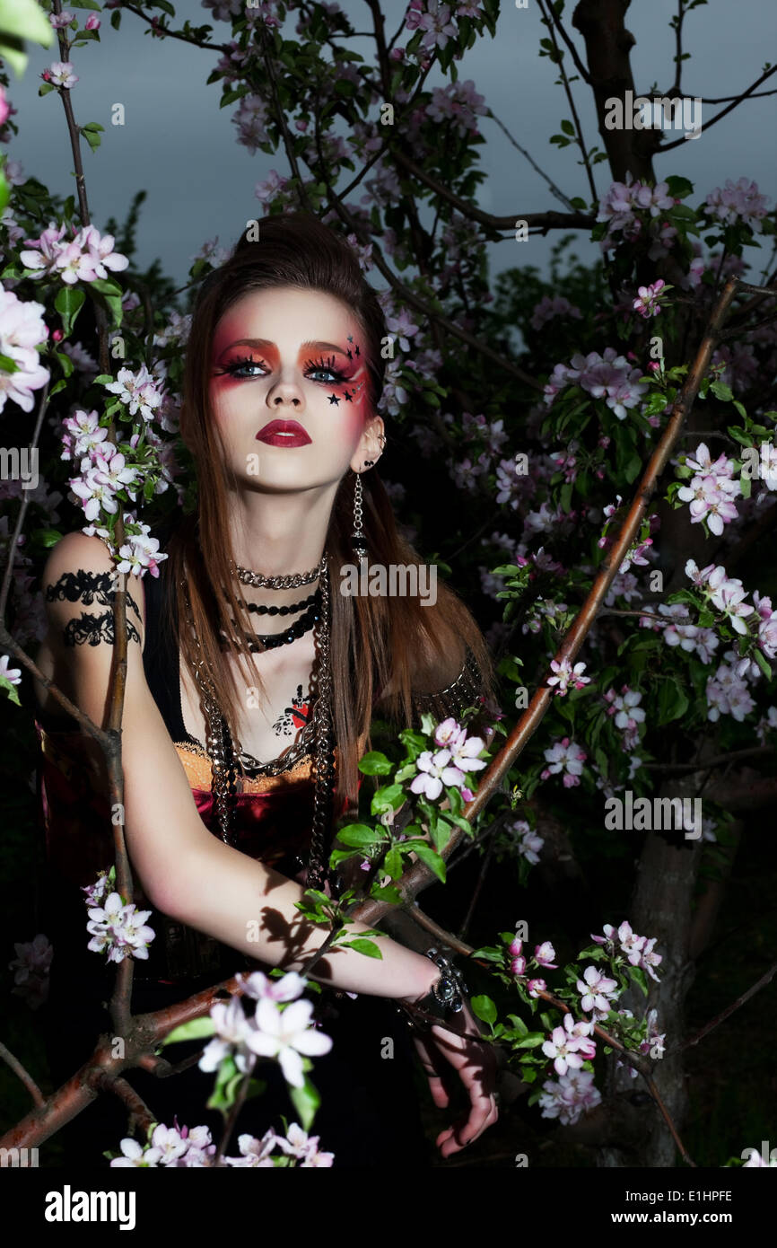 Belle jeune femme créative aux couleurs composent dans blooming garden apple Banque D'Images