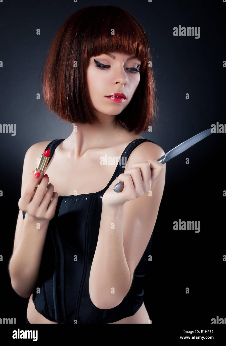 Belle fille de perruque de cheveux rouge mise sur make up - reflète le couteau de table Banque D'Images