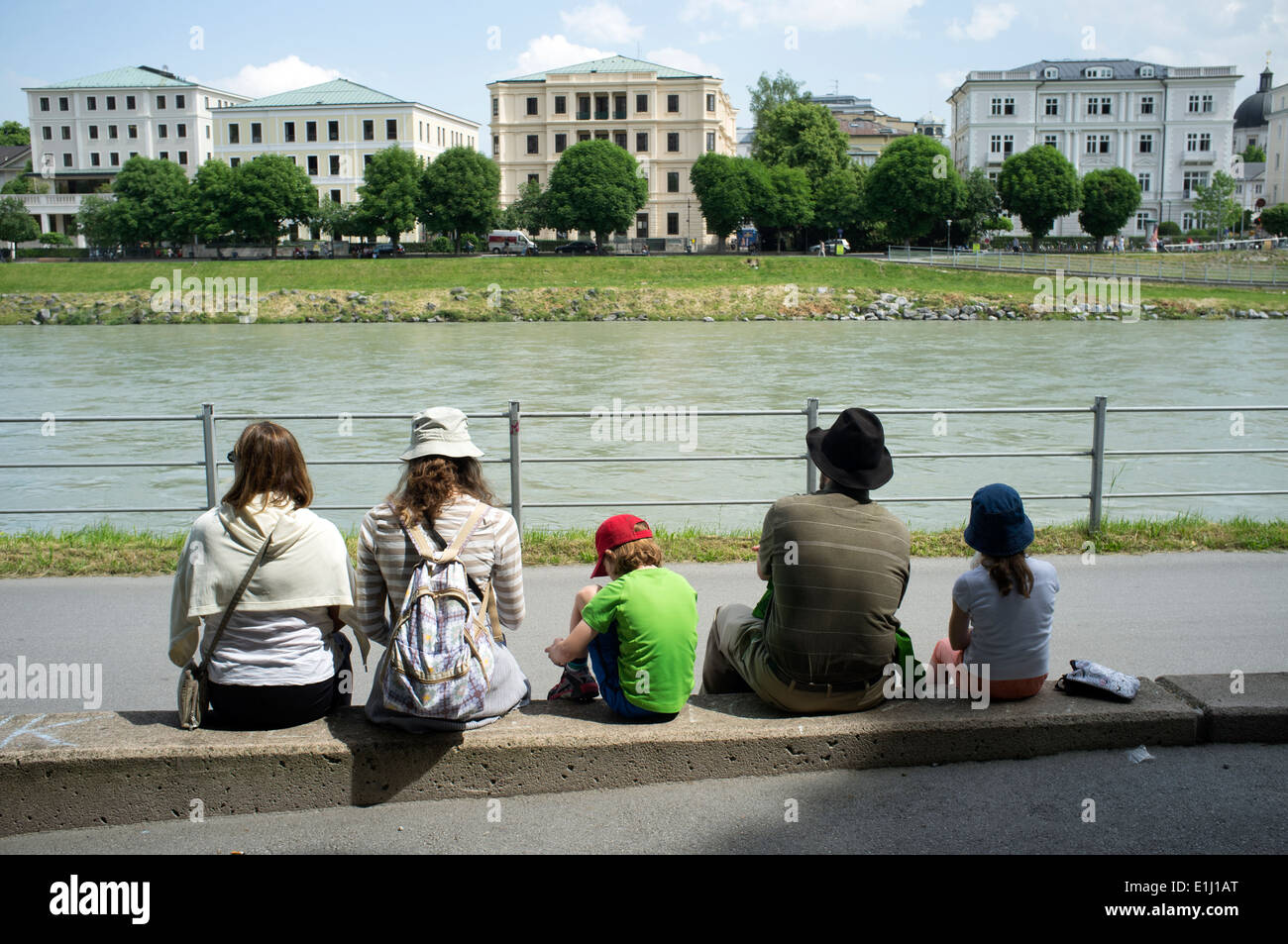 Famille assis sur les rives de la Salzach, à Salzbourg, en Autriche. Banque D'Images