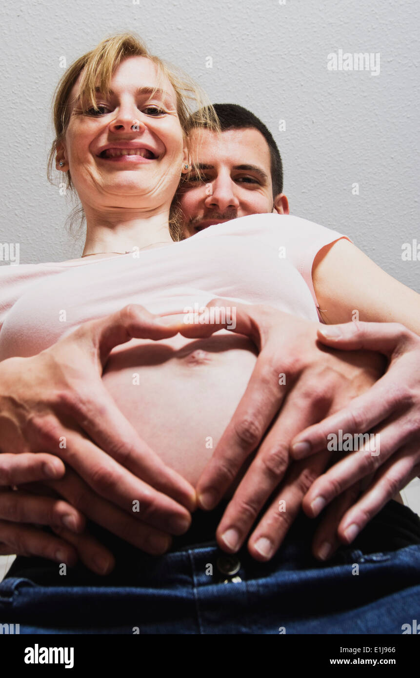 Heureux couple expecting a baby formant coeur avec les doigts Banque D'Images