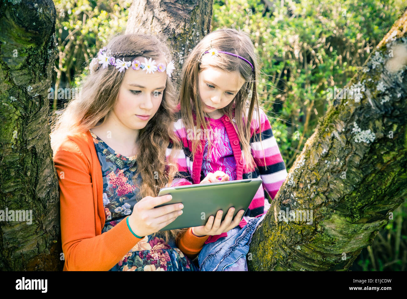 Deux soeurs avec tablet computer together in garden Banque D'Images