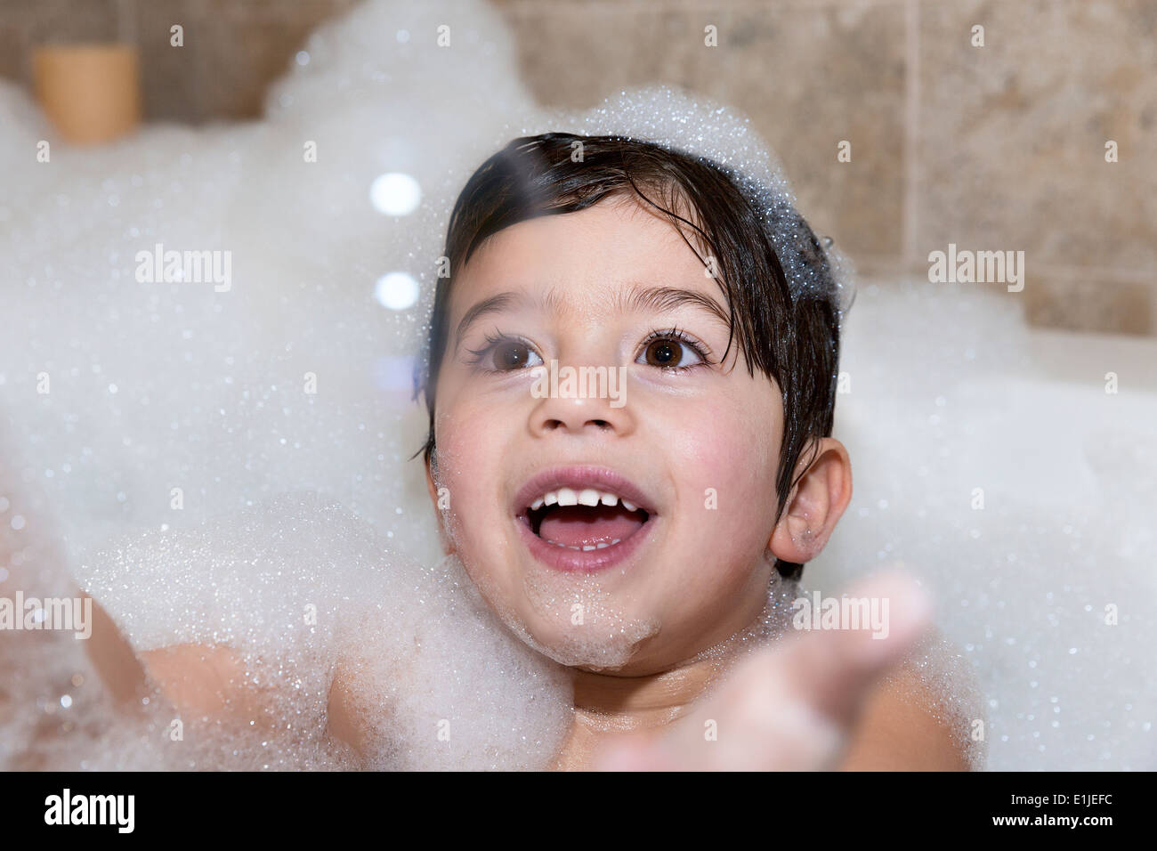 Jeune garçon essayant d'attraper bubble in bubble bath Banque D'Images