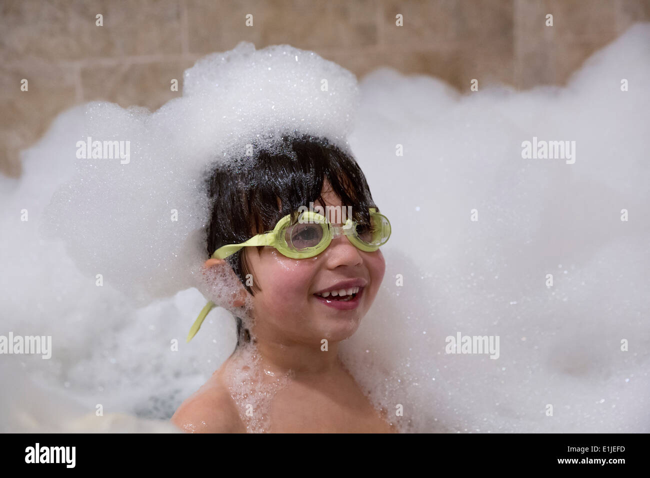 Portrait de jeune garçon portant ces lunettes in bubble bath Banque D'Images