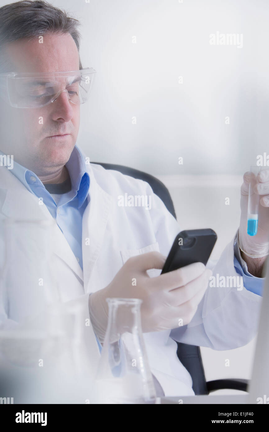 Scientist holding smartphone and test tube Banque D'Images
