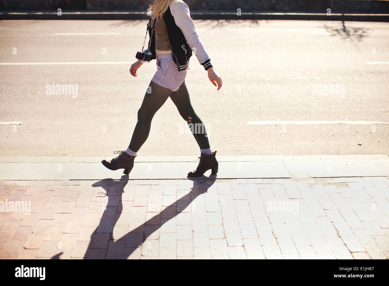 Jeune femme avec caméra walking down street Banque D'Images