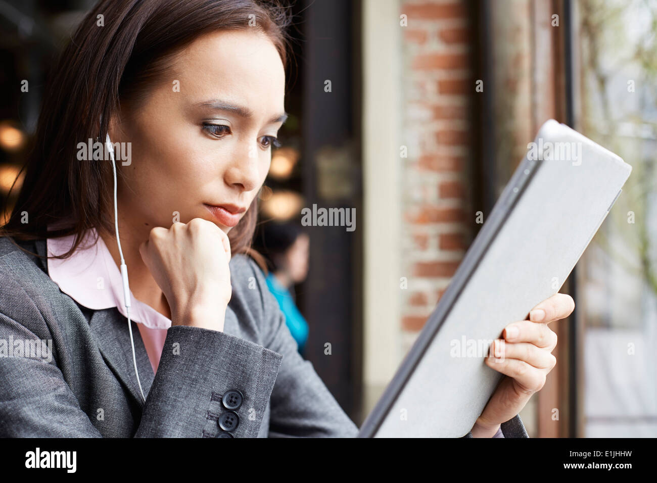 Jeune femme businesswoman with earphones reading paperwork in cafe Banque D'Images