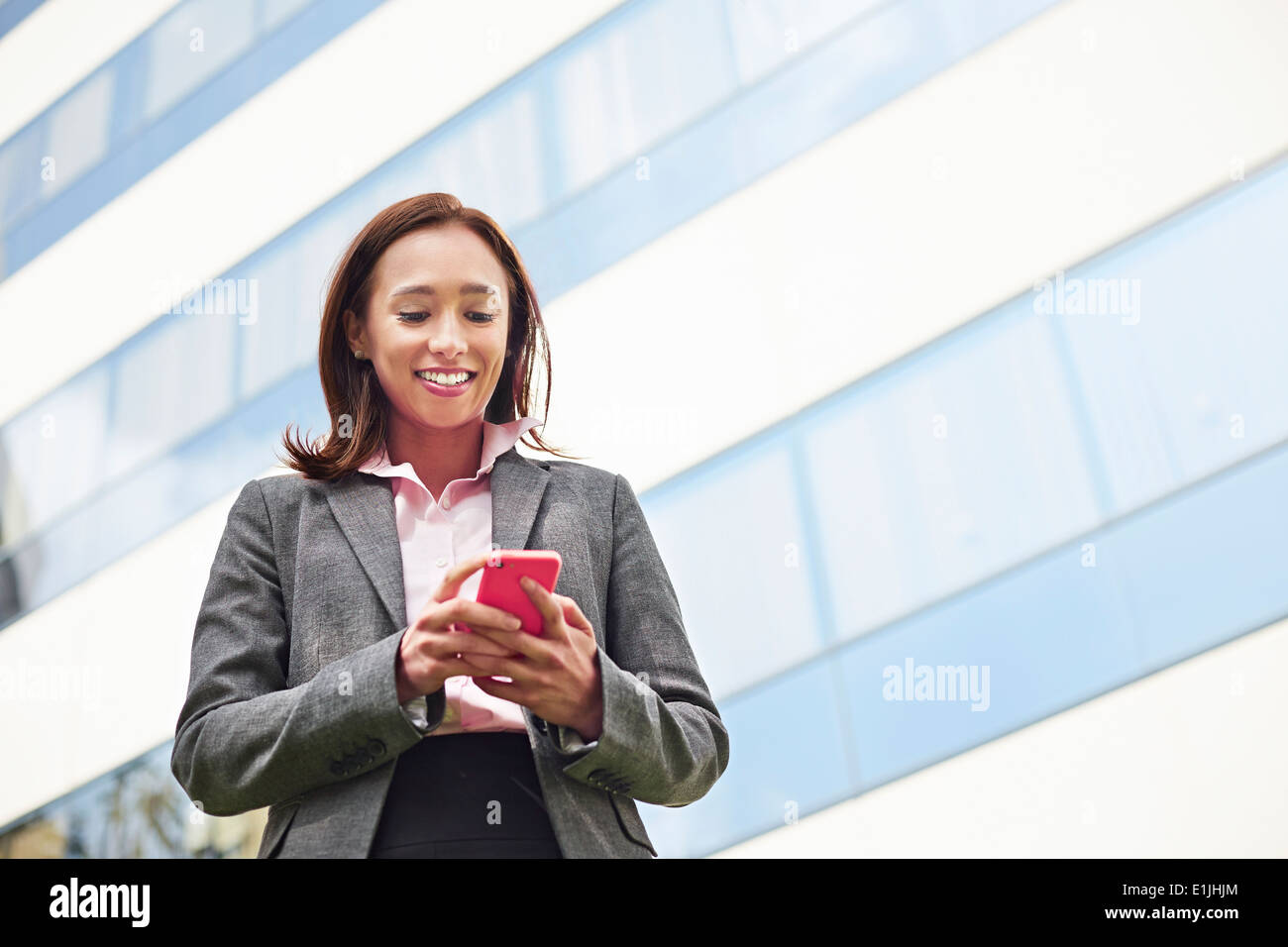 Jeune femme businesswoman texting on smartphone outside office Banque D'Images