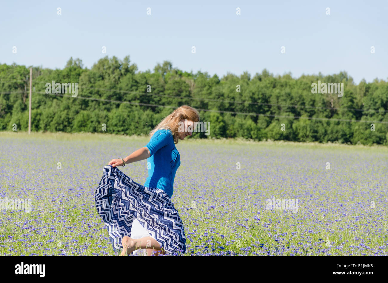 Jeune fille danse dans le bleuet sans fin de l'heure d'été prés Banque D'Images