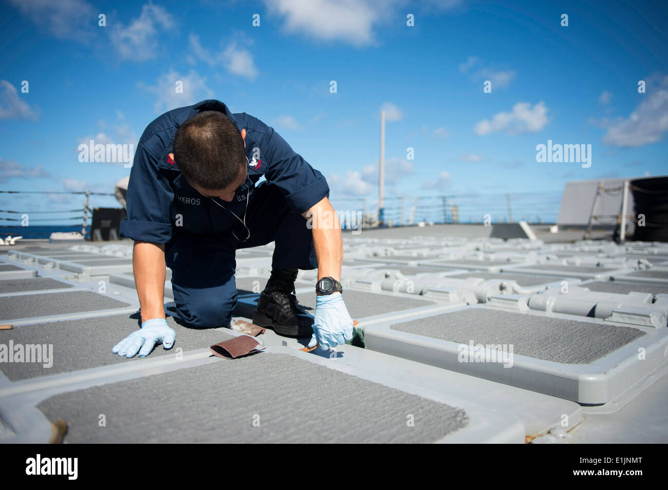 Gunner's Mate 2e classe Raymond Oliveros sands off la corrosion d'un système de lancement vertical à bord de la classe Arleigh Burke- guidée Banque D'Images