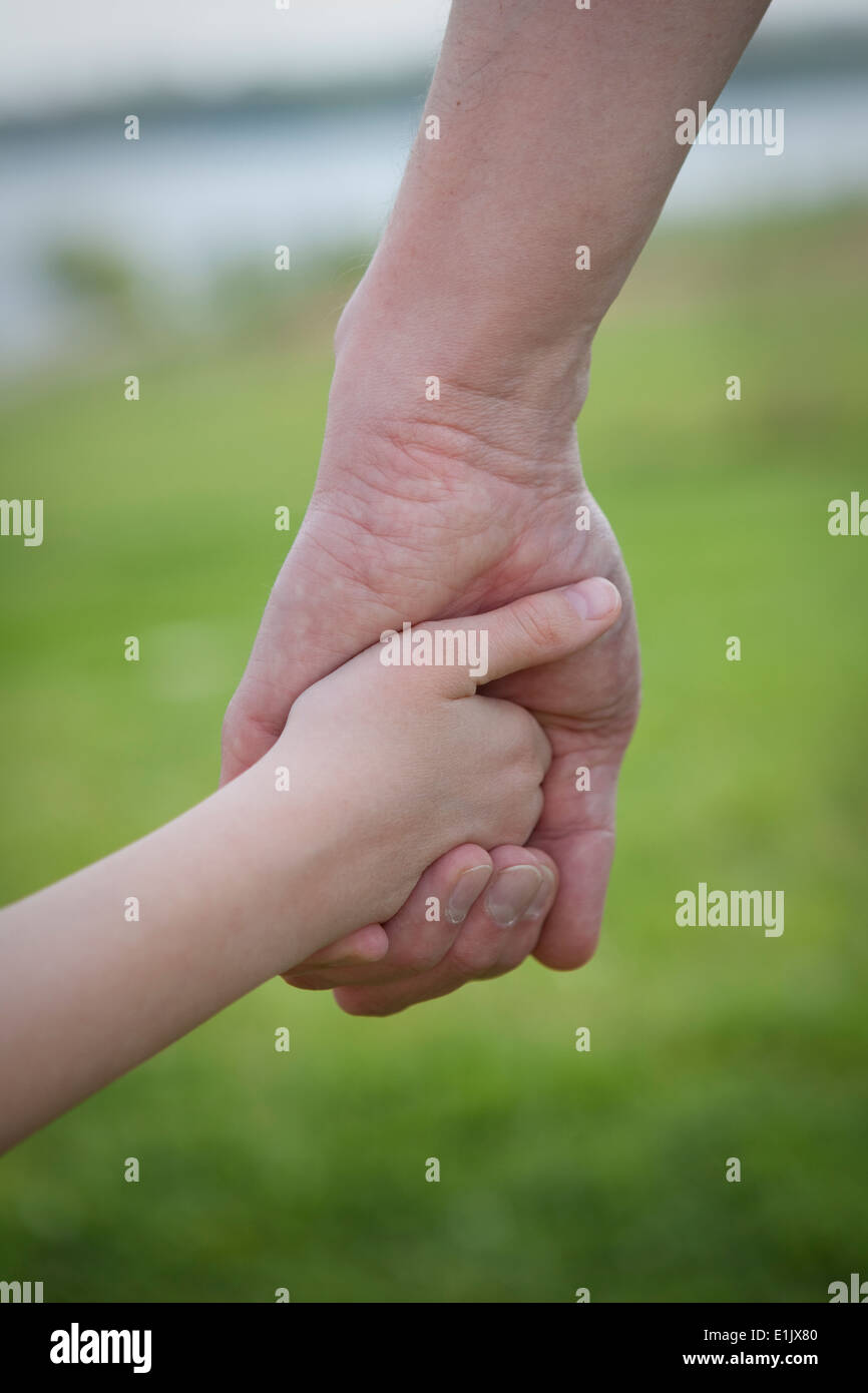 Close up d'un parent et l'enfant se tenir la main, à l'extérieur. Banque D'Images