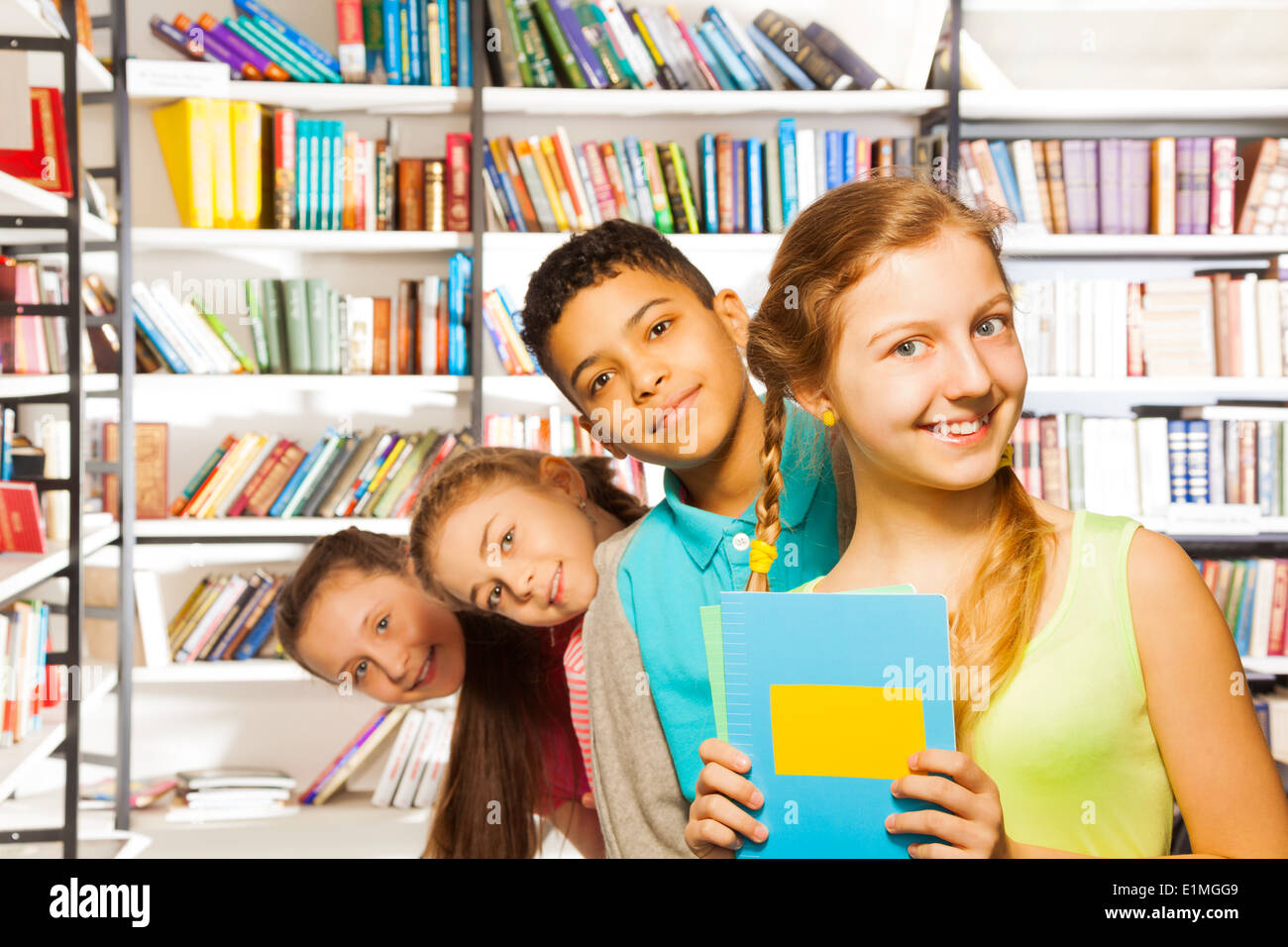 Quatre enfants se tenant dans une rangée à l'intérieur bibliothèque Banque D'Images