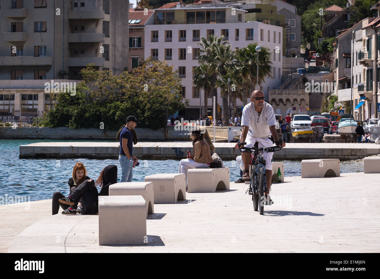 Un homme est passé à vélo vu un groupe de jeunes gens à Matejuska à l'ouest de Split en Croatie Riva Banque D'Images