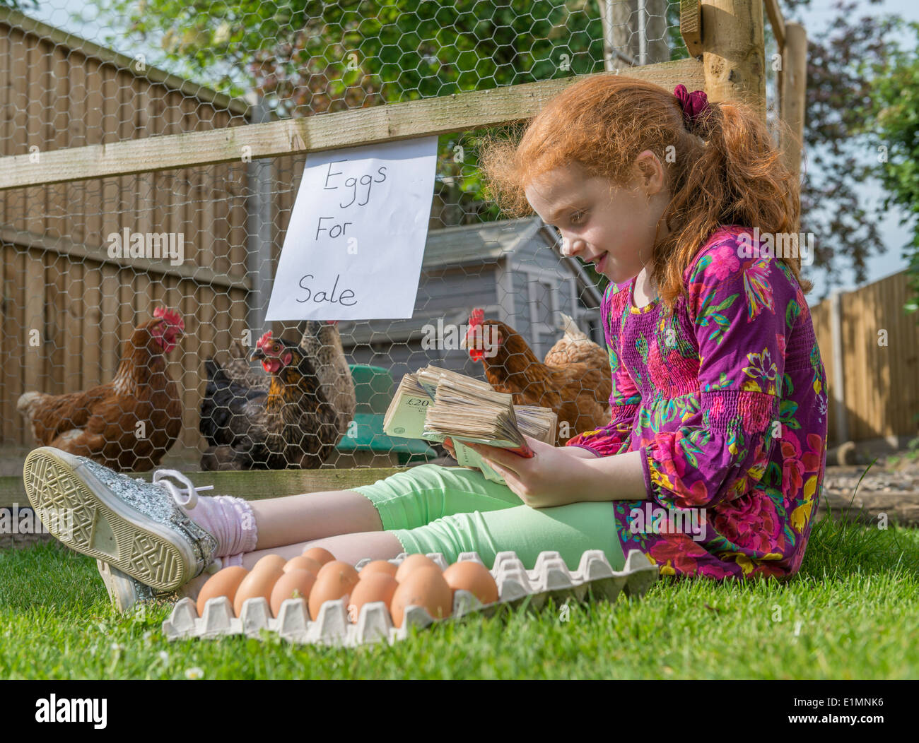 Petite fille entrepreneur siège avec des milliers de livres, tout en vendant des oeufs de poules. Banque D'Images
